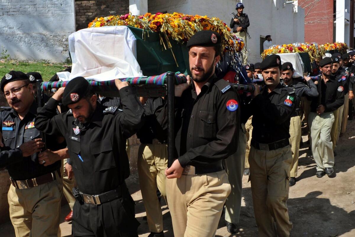Pakistani security officials carry the coffins of police officers killed in a suspected militant attack the day before near Peshawar.