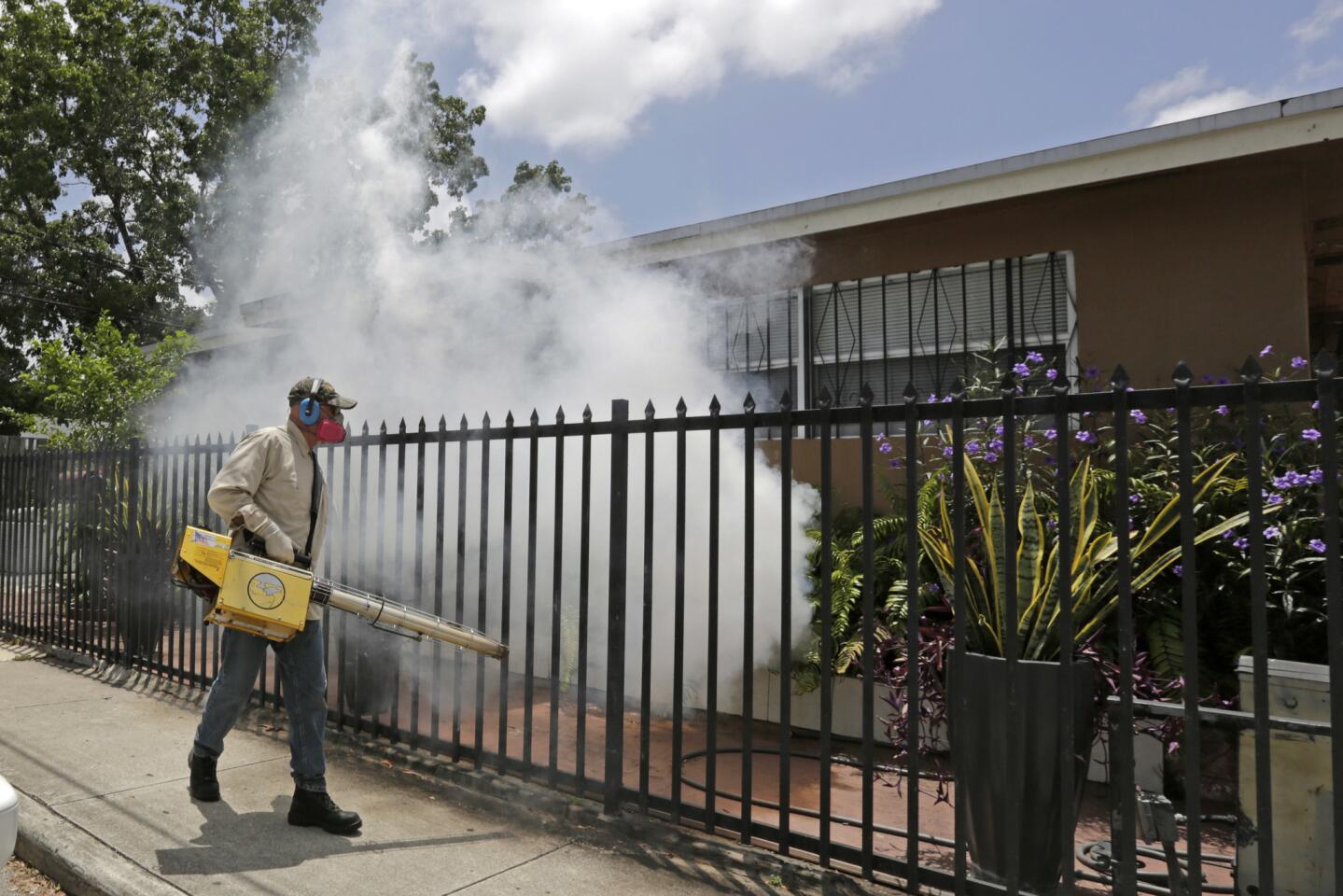 A Miami-Dade County mosquito control worker sprays around a home in the Wynwood area of Miami on Aug. 1, 2016.