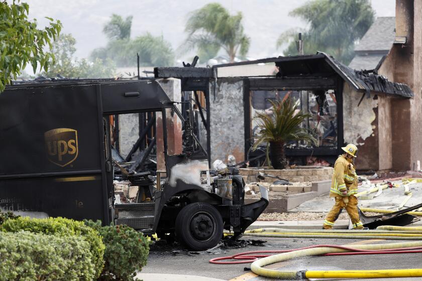 A firefighter walks by the debris of a fatal plane crash on Monday, Oct. 11, 2021 in Santee, CA. 