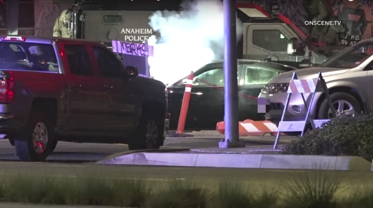 A cloud of smoke and chemicals rise from a car surrounded by other vehicles.