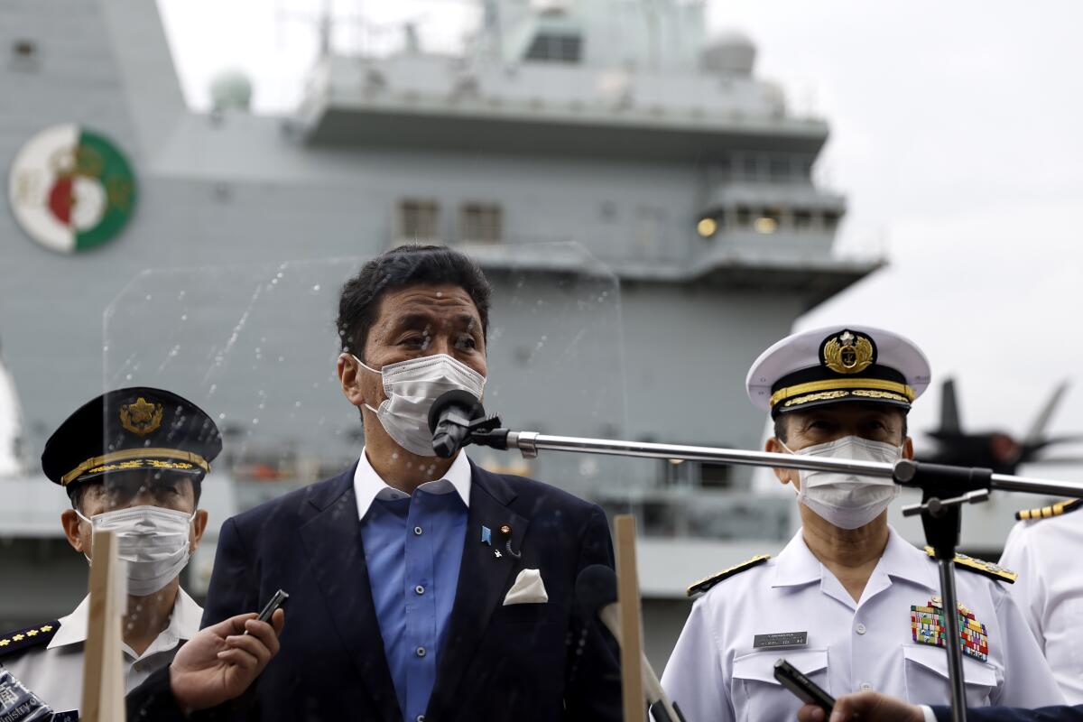 Japan Defense Minister Nobuo Kishi speaks to the members of the media after he inspected the British Royal Navy's HMS Queen Elizabeth aircraft carrier, back, at the U.S. naval base in Yokosuka, Kanagawa Prefecture, Japan Monday, Sept. 6, 2021. (Kiyoshi Ota/Pool Photo via AP)
