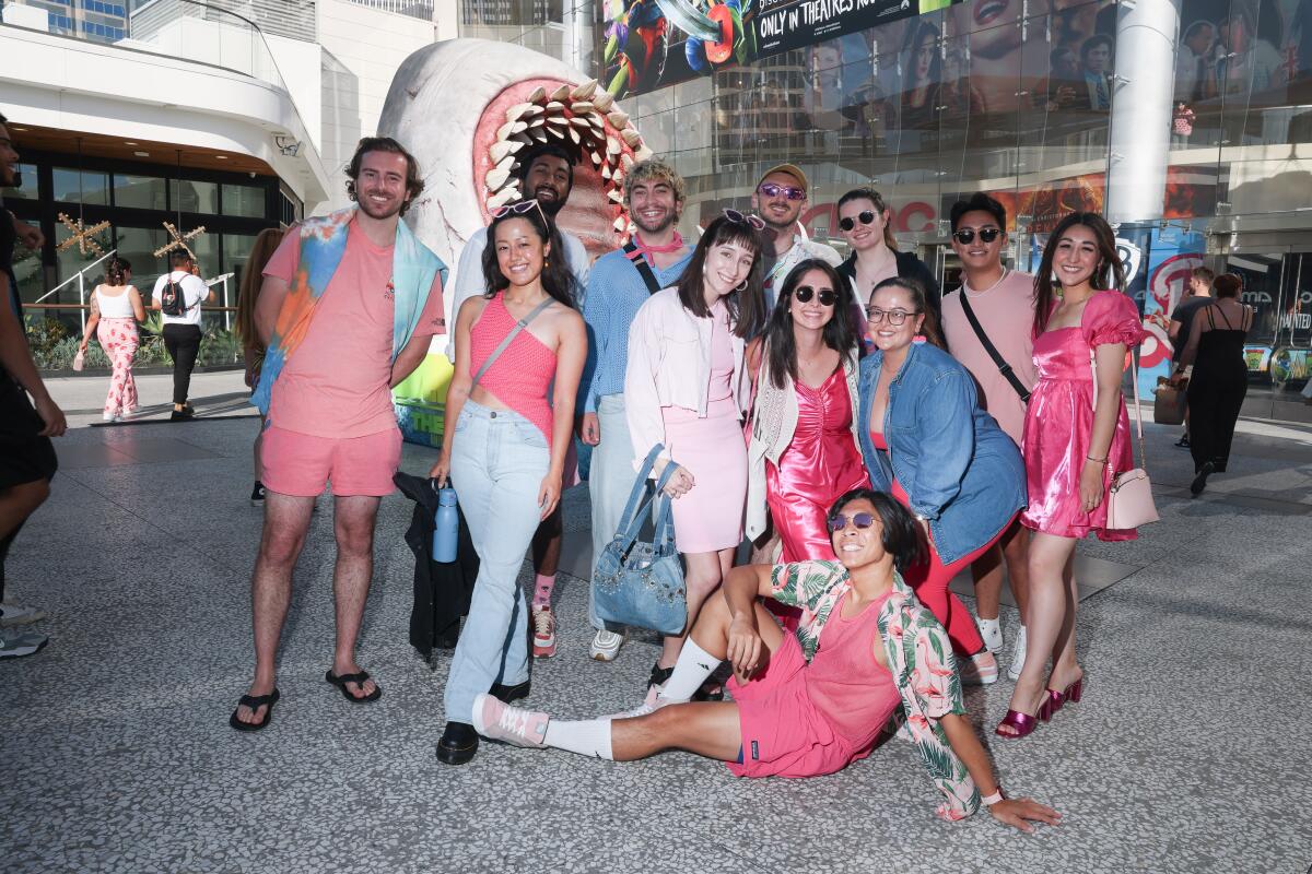 Several filmgoers dressed in pink pose outside a movie theater.