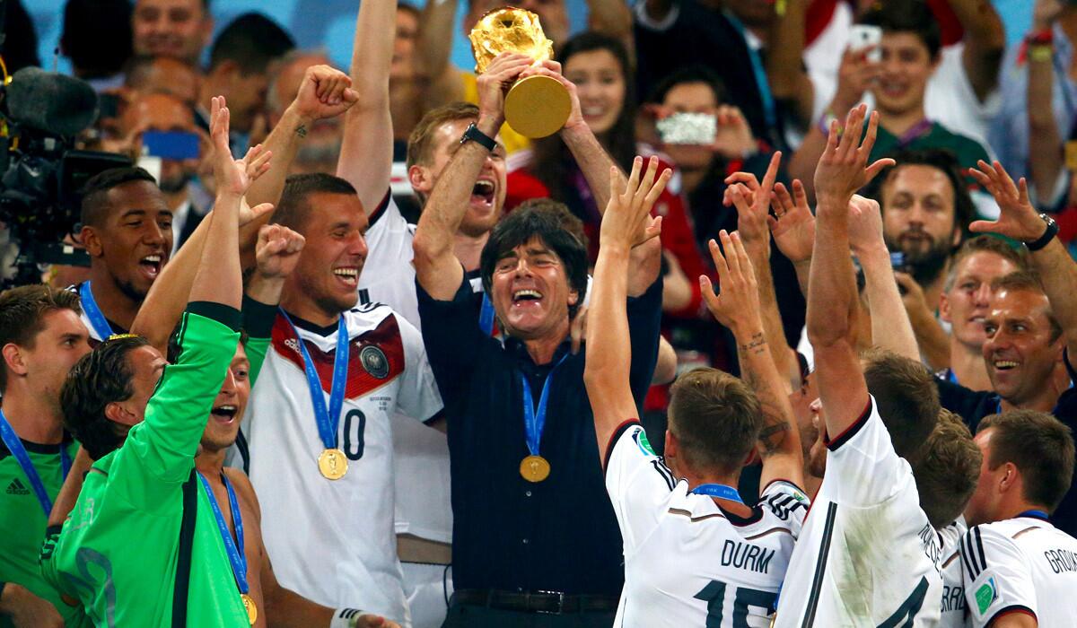 Germany Coach Joachim Loew raises the World Cup trophy as he's surrounded by his players following their 1-0 victory over Argentina in the championship game on Sunday at Maracana Stadium in Rio de Janeiro.