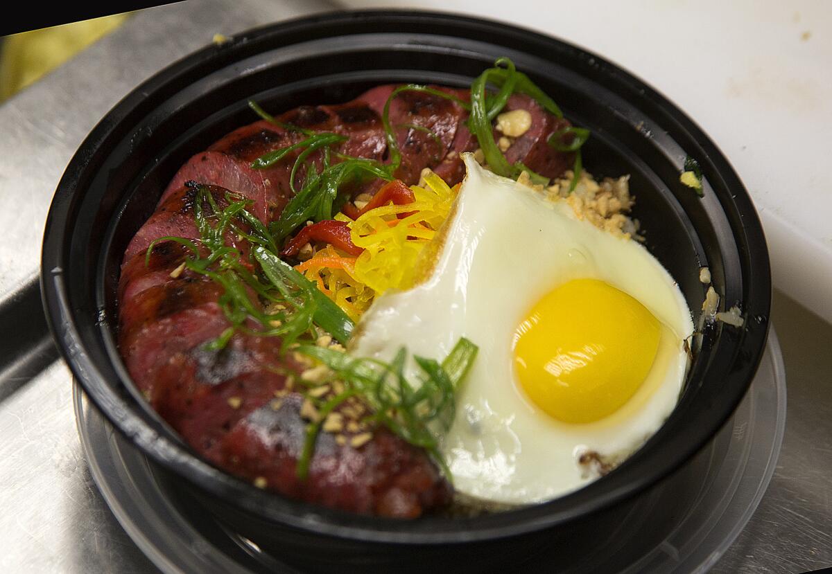 Pork longaniza is served with pickled vegetables, garlic crumbs and garlic fried rice at chef Charles Olallia's Rice Bar on 7th Street in downtown Los Angeles.