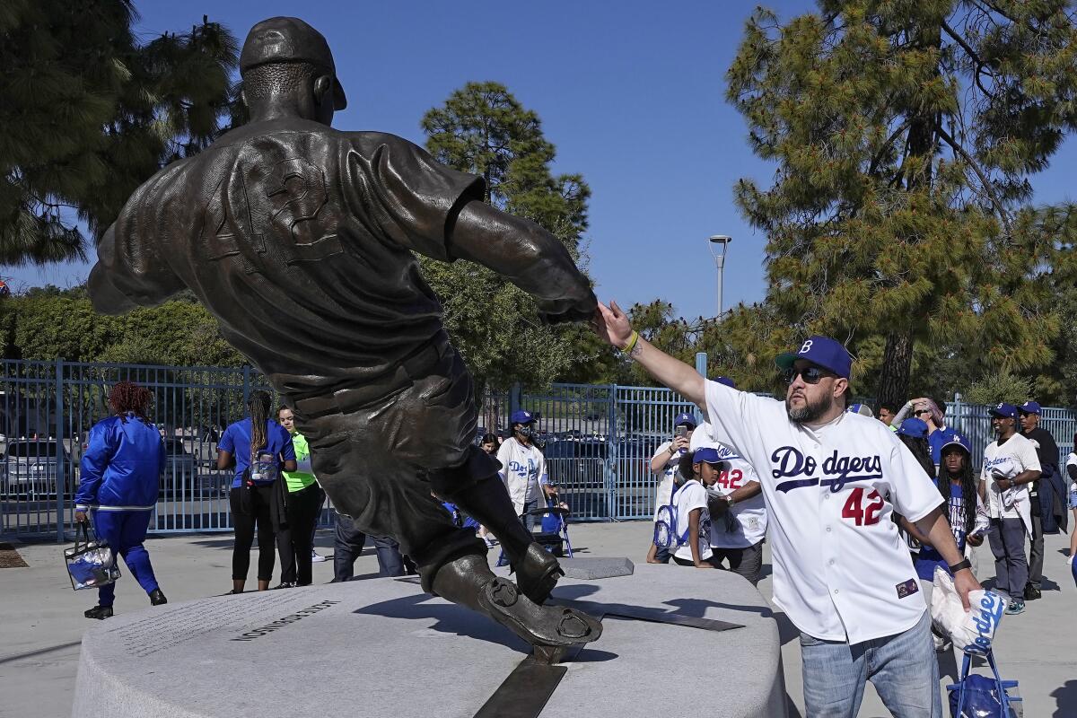 Dodgers fan Cesar Melgoza touches a statue of baseball great Jackie Robinson.