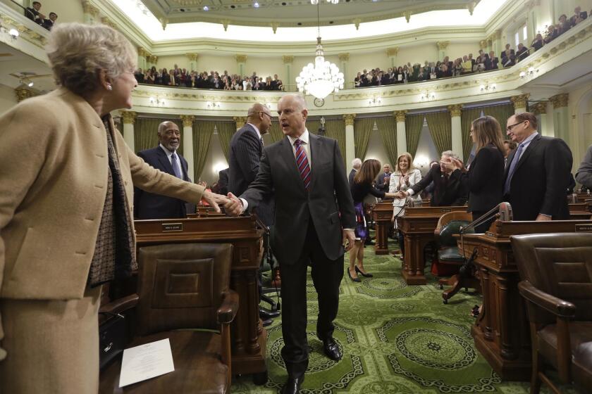 Gov. Jerry Brown, center, is greeted by lawmakers on the floor of the state Assembly before his inauguration at the state Capitol on Monday.