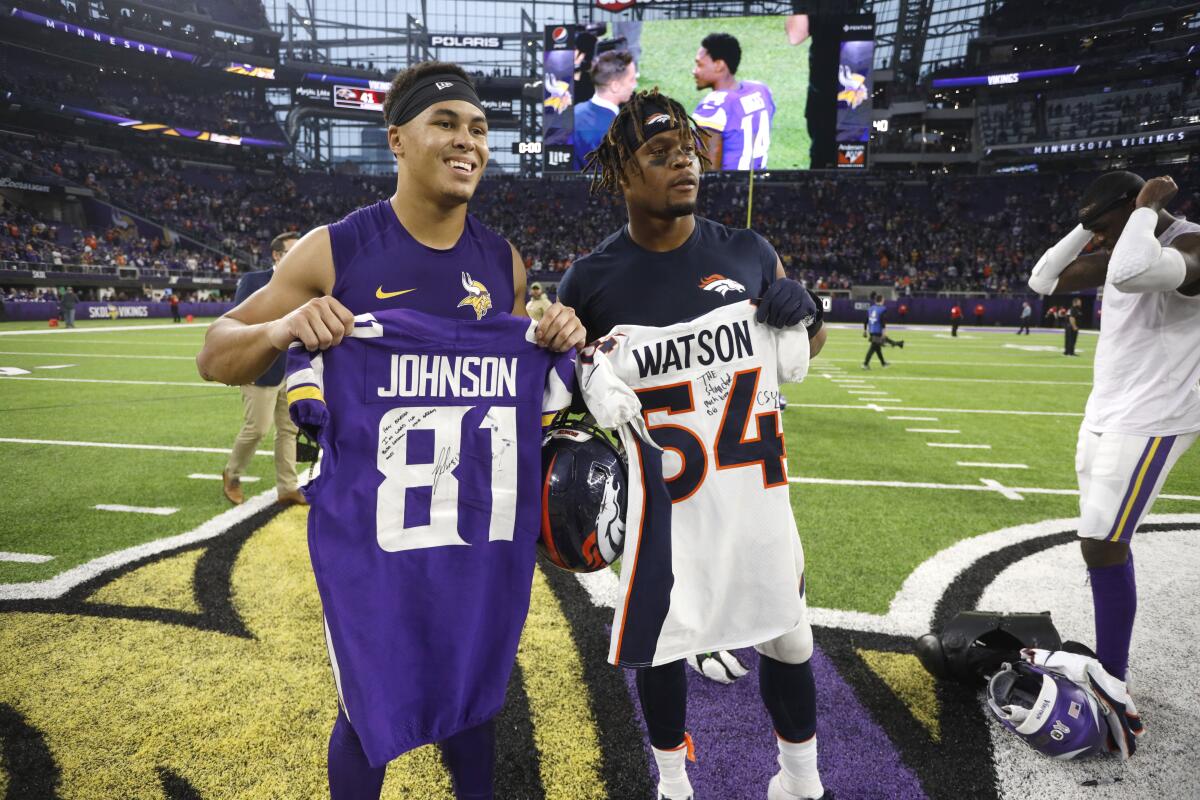 Minnesota Vikings wide receiver Bisi Johnson, left, and Denver Broncos linebacker Josh Watson pose after swapping jerseys.