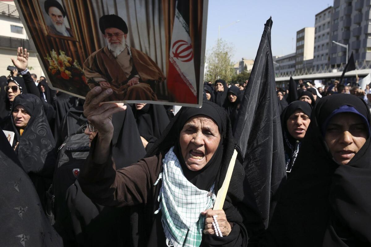 An Iranian woman holds a poster of Supreme Leader Ayatollah Ali Khamenei and late revolutionary founder Ayatollah Khomeini at an anti-Saudi rally in Tehran on Sept. 25.