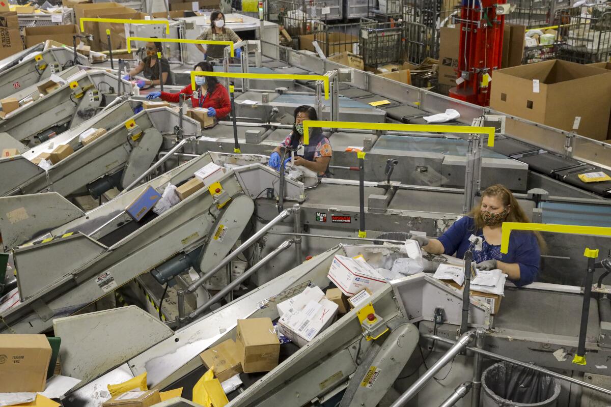 Packages move through large metal conveyor machines with a postal worker at each machine