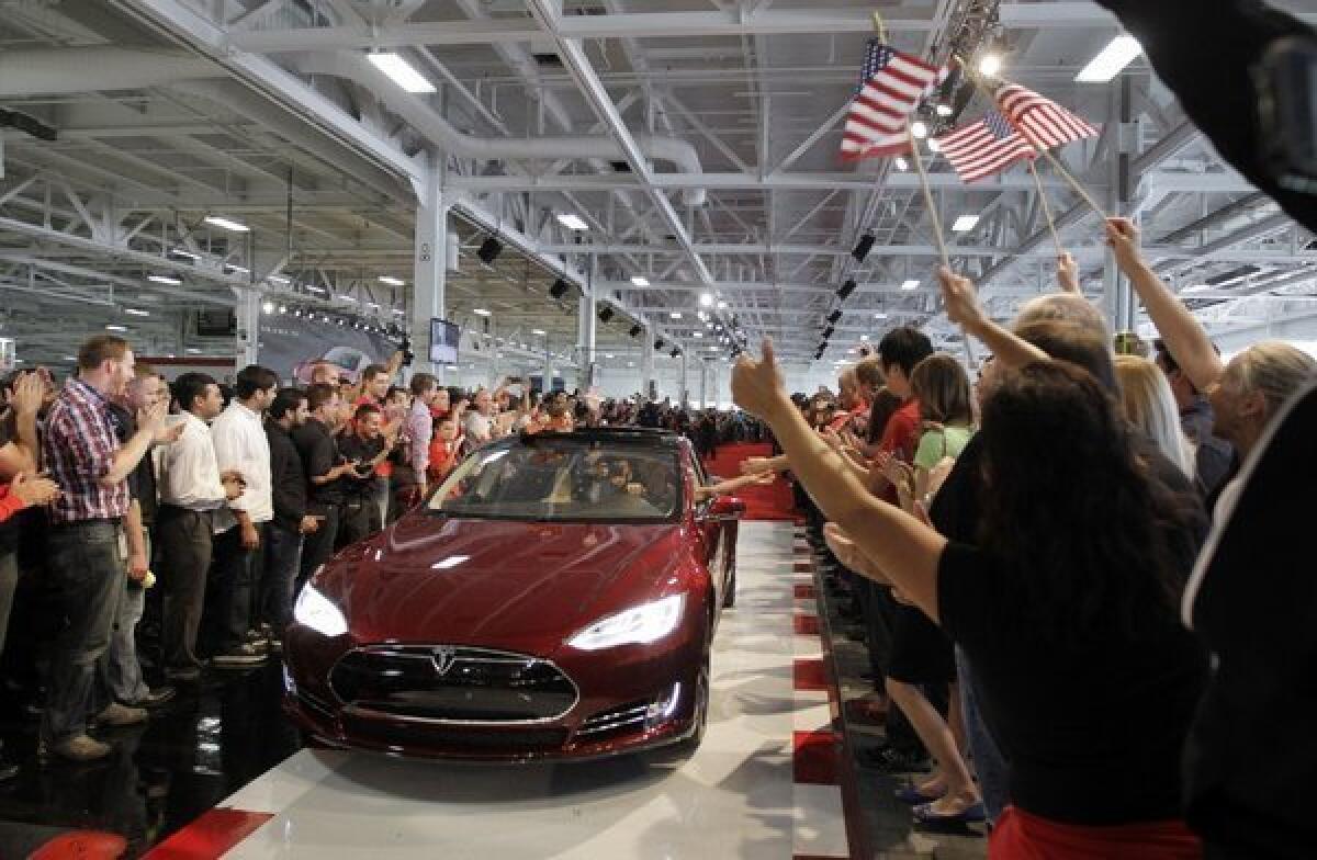 Tesla workers cheer the first Model S cars sold during a rally at the company's factory in Fremont, Calif.