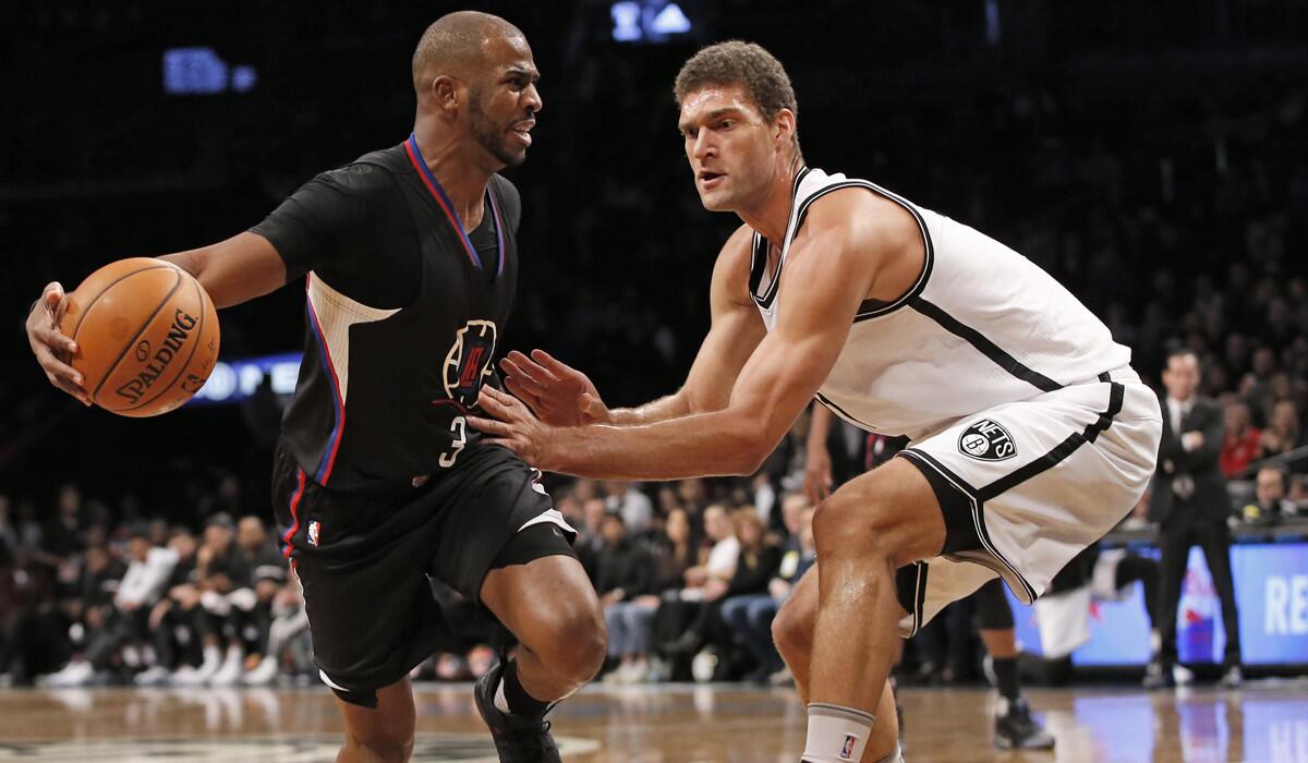 Clippers guard Chris Paul, left, looks for a path around Brooklyn Nets center Brook Lopez during the first half Tuesday.