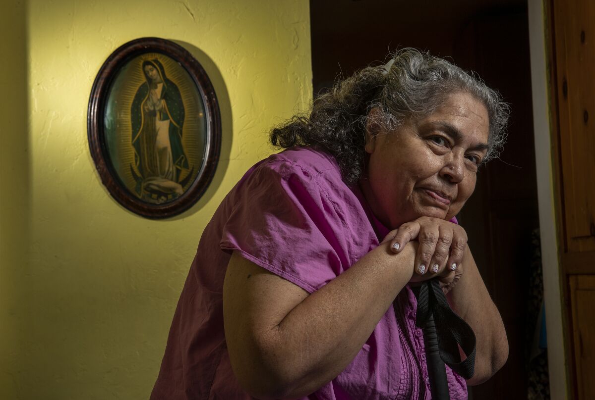 A woman leaning on a cane near mounted religious art.
