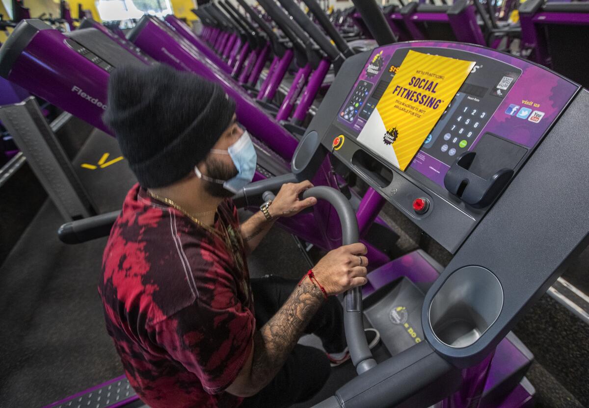 Jose Pineda, an employee at Planet Fitness on Imperial Highway in Inglewood prepares to lift another treadmill.