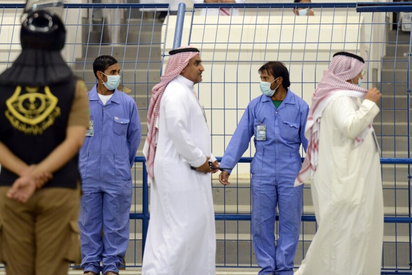 Asian workers wear mouth and nose masks while on duty during a football match at the King Fahad stadium in Riyadh.