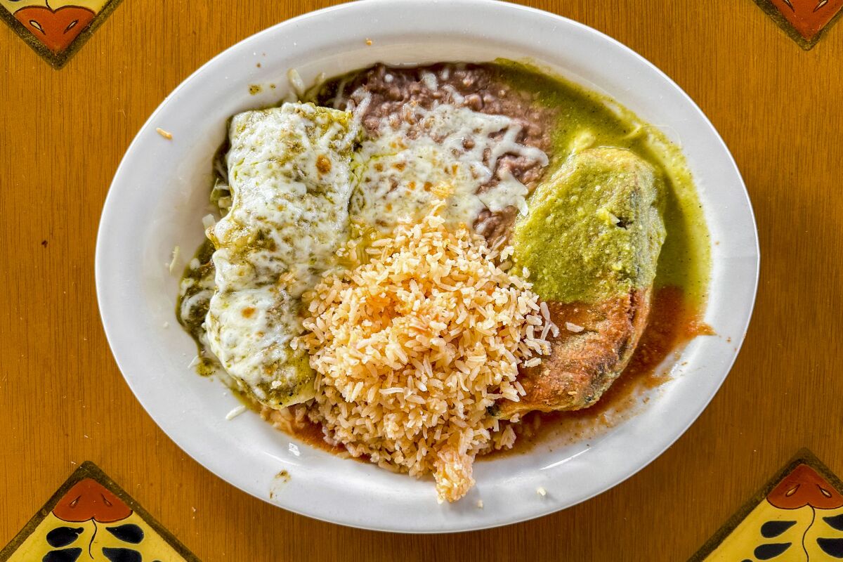 A combination plate of pork chile verde enchilada and chile relleno with rice and beans