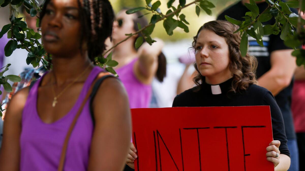 Methodist pastor Colleen Bookter holds a "Unite" sign during a rally at Louisiana State University.