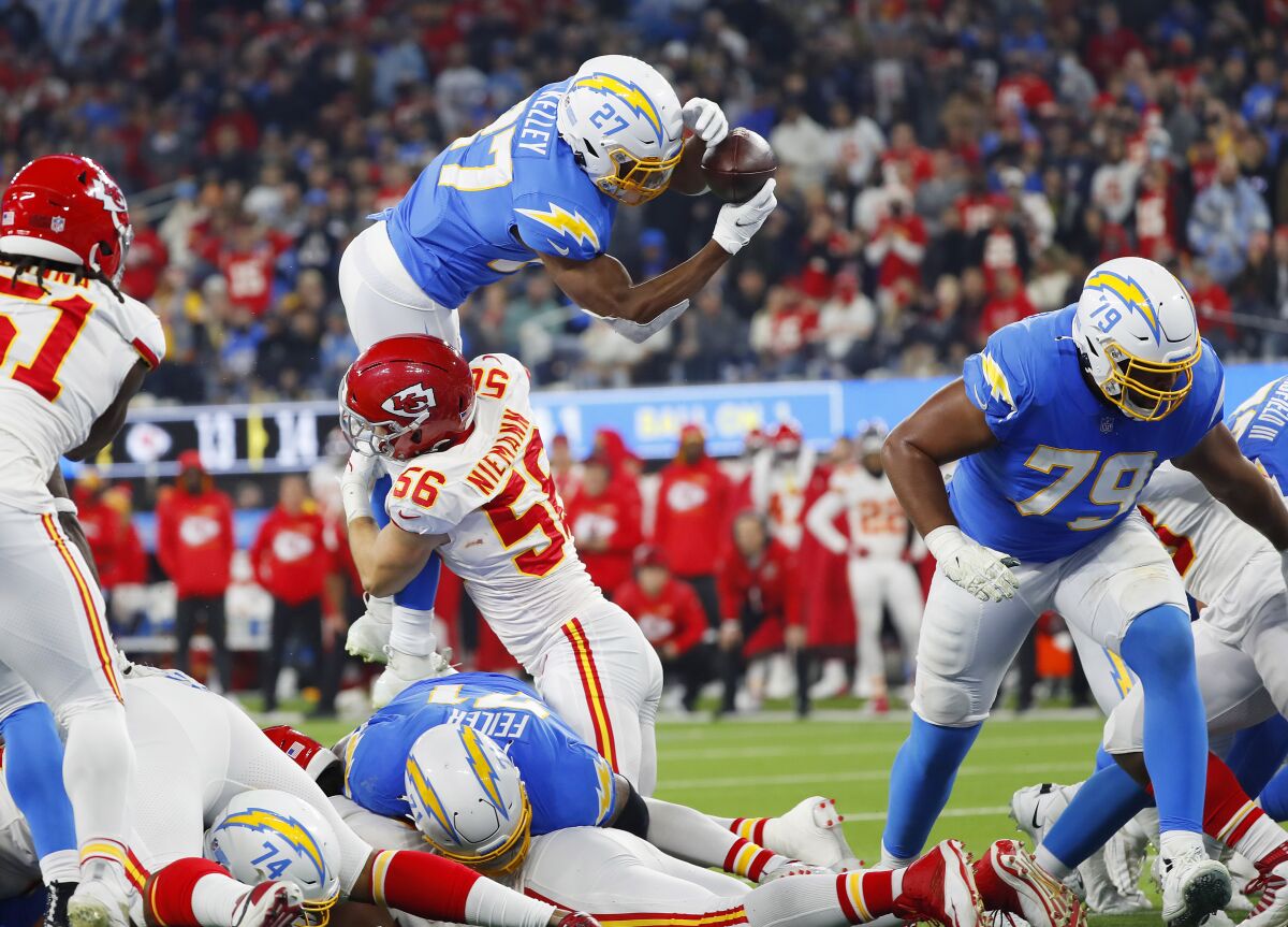 Chargers' Joshua Kelley goes up and fumbles after being hit by Kansas City Chiefs' Ben Niemann at SoFi Stadium.