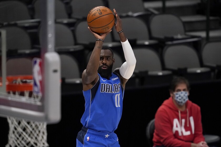 Dallas Mavericks forward Tim Hardaway Jr. (11) shoots as team owner Mark Cuban watches during the first half of the team's NBA basketball game against the Golden State Warriors in Dallas, Thursday, Feb. 4, 2021. (AP Photo/Tony Gutierrez)