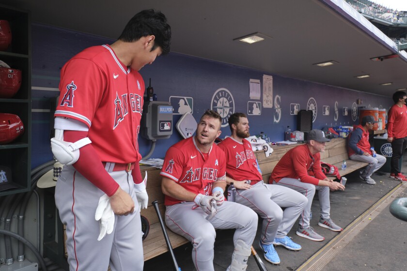 Mike Trout talks with Angels teammate Shohei Ohtani, left, in the dugout.