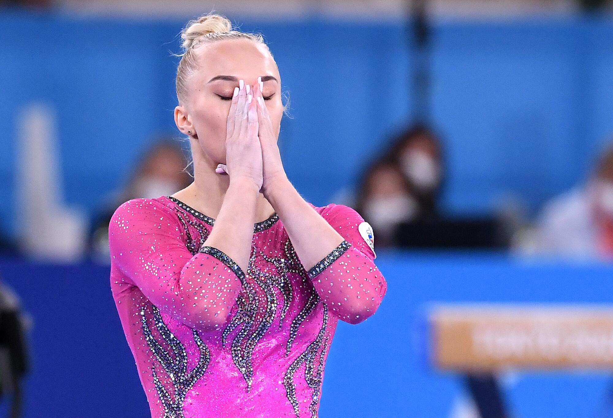 Angelina Melnikova holds her hands to her face during gymnastics at the Tokyo Olympics.