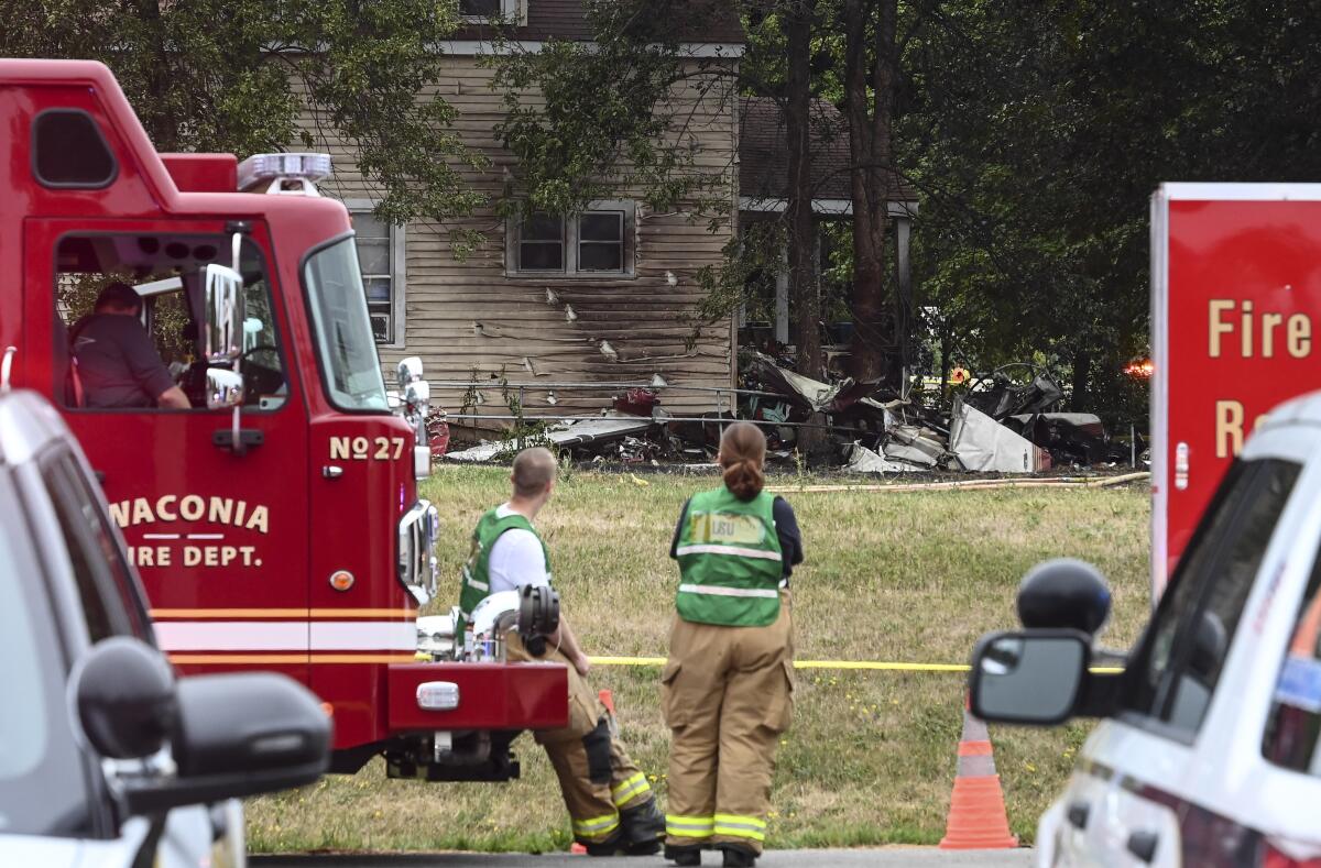 Firefighters look on at the scene of a plane crash, Sunday, Aug. 8, 2021 in Victoria, Minn. Three people died when a single-engine plane crashed into a vacant lot and burst into flames in a small southeastern Minnesota city, a National Transportation Safety Board official said Sunday.(Aaron Lavinsky/Star Tribune via AP)