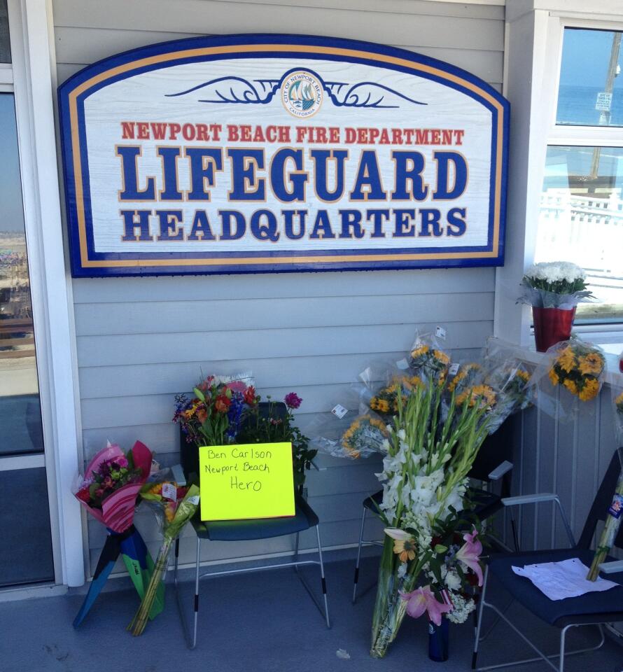 Flowers, some stuffed into swim fins, are left outside lifeguard headquarters in Newport Beach.