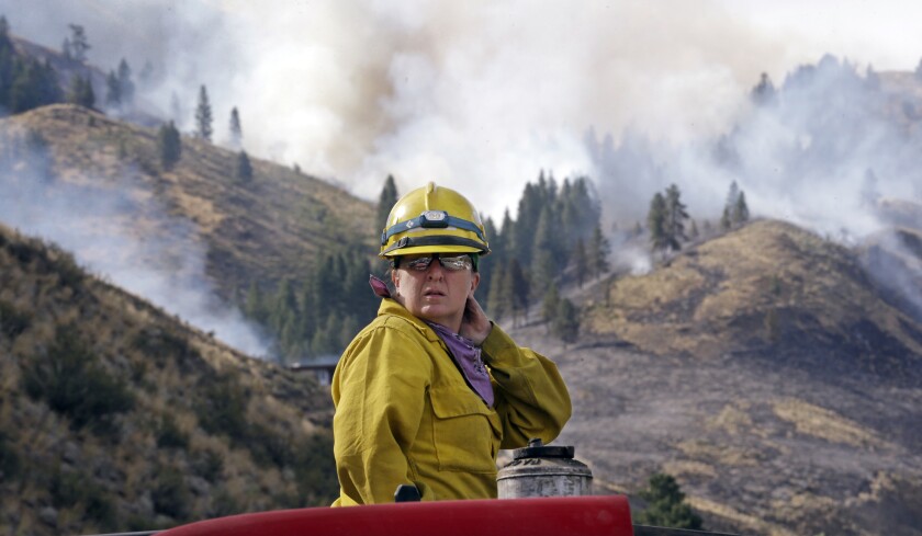 Firefighter Kathleen Calvin surveys the smoky scene around her from atop a fire truck as she waits to begin battling the Carlton Complex fire near Winthrop in north-central Washington.