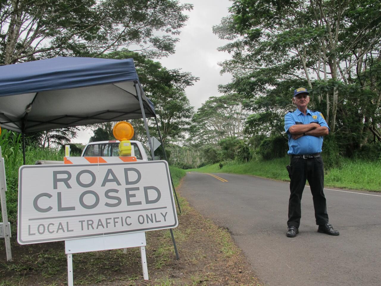 Security guard George Cortez stands at a roadblock to prevent nonresidents from entering the lava-threatened community of Kaohe Homesteads in Pahoa, Hawaii.