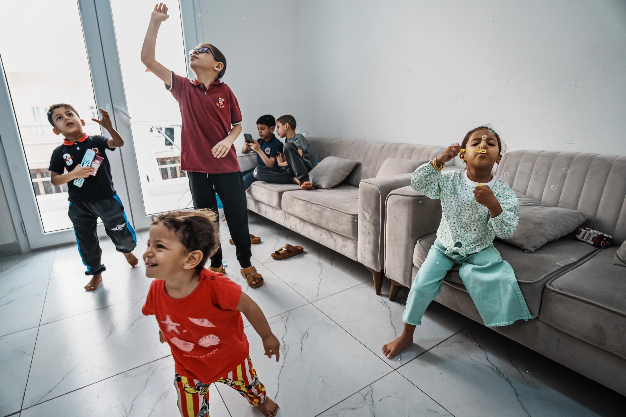 六个孩子在公寓的瓷砖地板上或沙发上玩耍时吹泡泡。 
