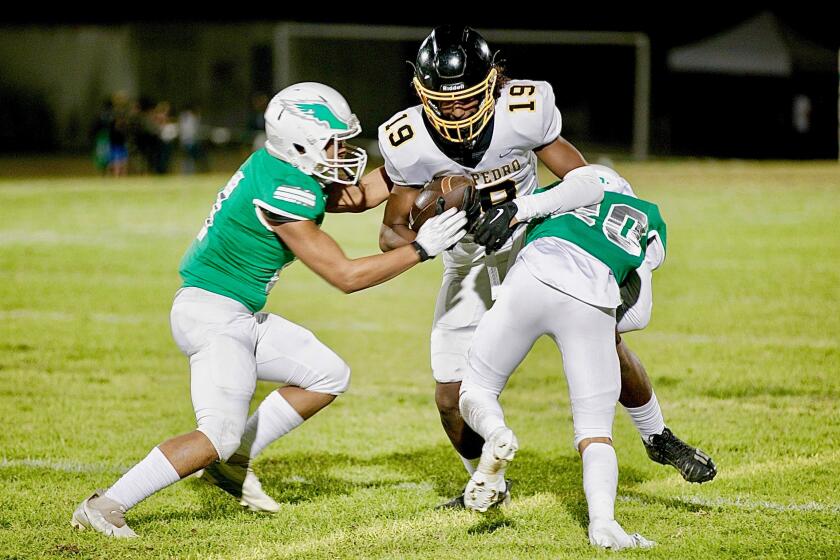 San Pedro receiver Elias Redlew is tackled by Eagle Rock’s Jason Terrazas and Jonathan De La Paz on Friday night.