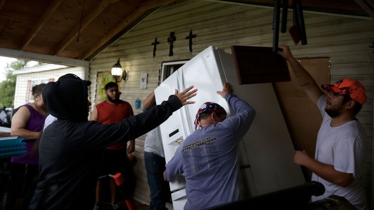 The Gonzalez family lift a refrigerator as they prepare to evacuate their home on the banks of the Brazos River.