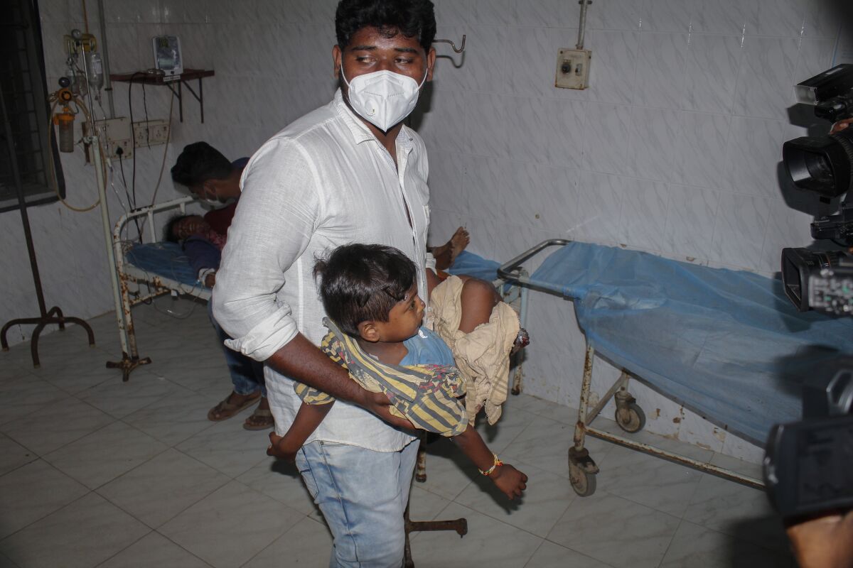 A young patient is carried by a man at the district government hospital in Eluru, Andhra Pradesh state, India, Monday, Dec.7, 2020. Health officials and experts are still baffled by a mysterious illness that has left over 500 people hospitalized and one person dead in this southern Indian state. (AP Photo)