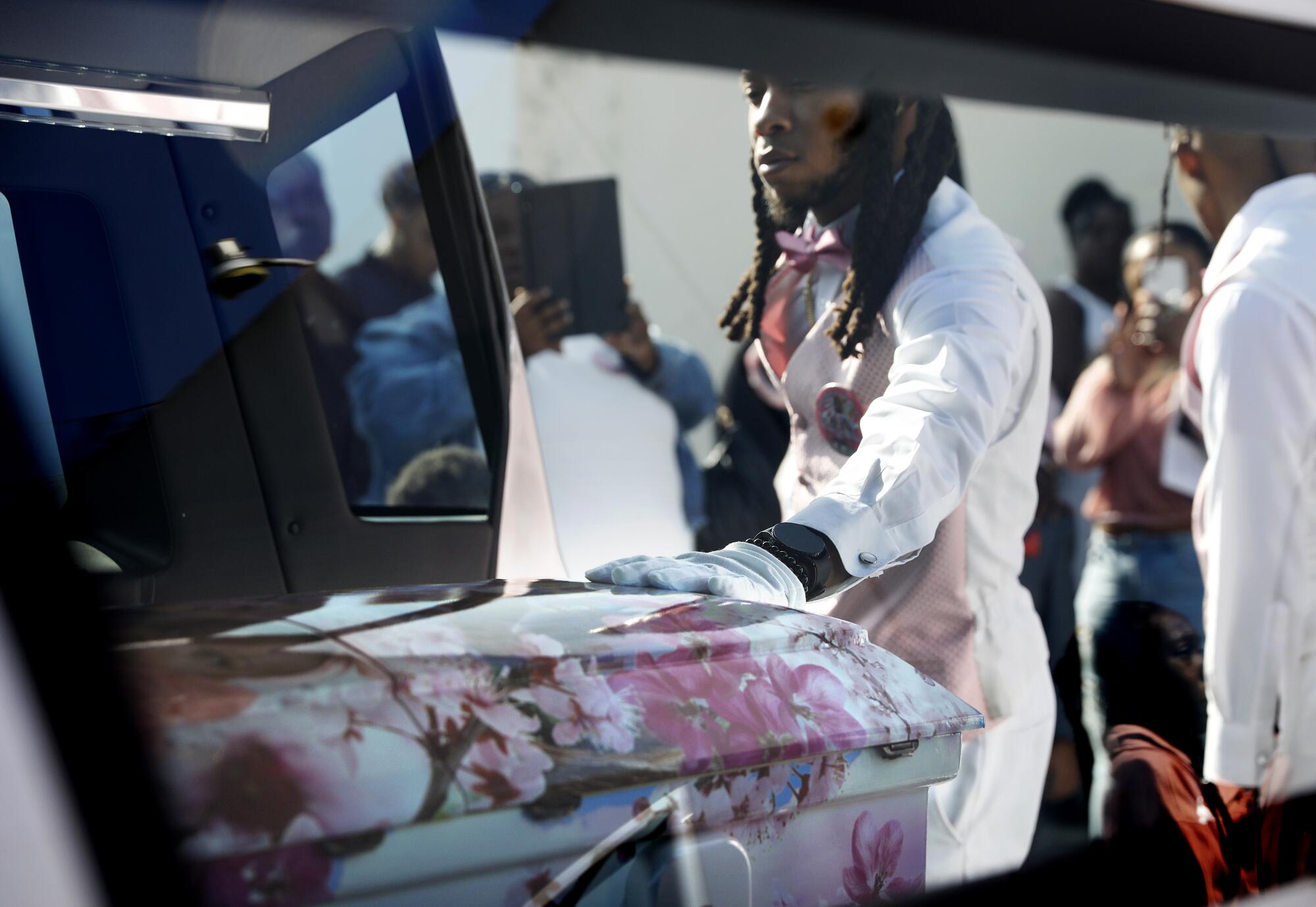 A person places a hand on a casket.