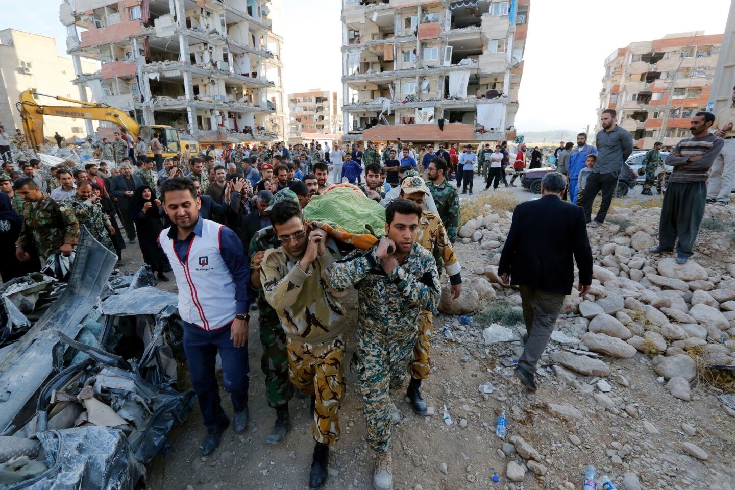 Iranian soldiers carry the body of an earthquake victim near the wreckage of a collapsed building in the city of Pole-Zahab, in Kermanshah province, Iran, on Nov. 13. A 7.2 magnitude earthquake that struck Iran's the province bordering Iraq has killed more than 328 people and left at least 3,950 injured, Iranian authorities said.
