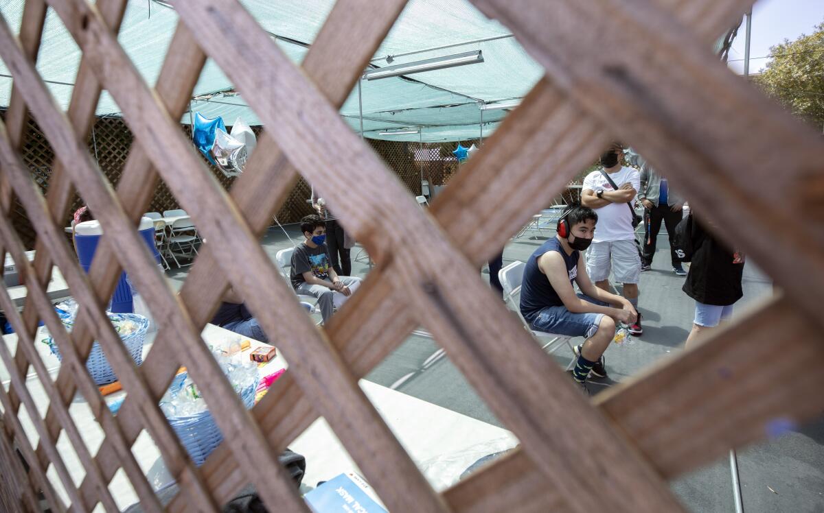 Two boys sit under a tent.