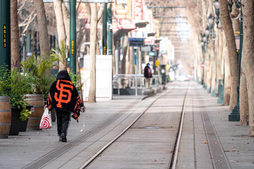 A person walks along a Santa Clara Valley Transportation Authority (VTA) track in downtown in San Jose, California, U.S., on Wednesday, Jan. 6, 2021. California reported 459 daily virus deaths, the second-highest tally since the pandemic began, as the most-populous state continues to battle a surge of cases that has strained health-care facilities. Photographer: David Paul Morris/Bloomberg via Getty Images