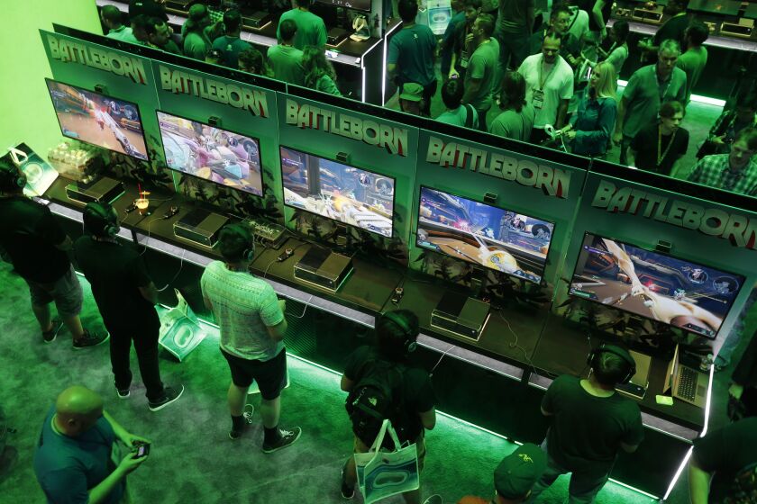 Video game enthusiasts line up at the Xbox booth during the Electronic Entertainment Expo in June. Xbox maker Microsoft and PlayStation’s Sony appear to be pricing consoles to appeal to new players.