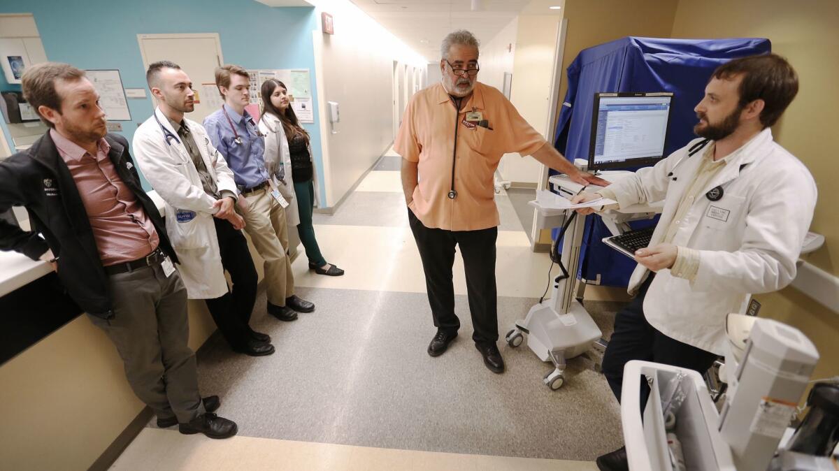 Resident physicians listen to Dr. Jonathan LoPresti, center, who's been at Los Angeles County-USC Medical Center for 36 years, and resident physician Hugh Gordon, right, as they discuss patient care.