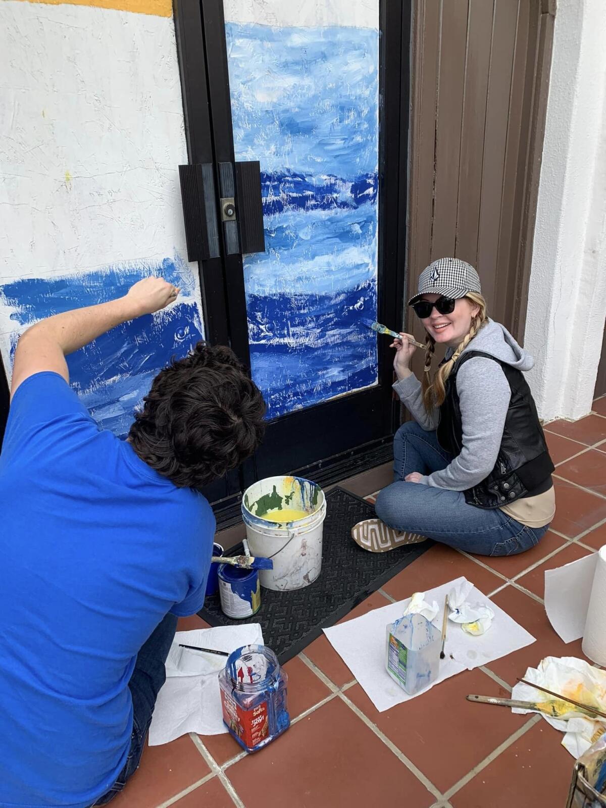Volunteers help paint murals on the doors of the Christ Church by the Sea.