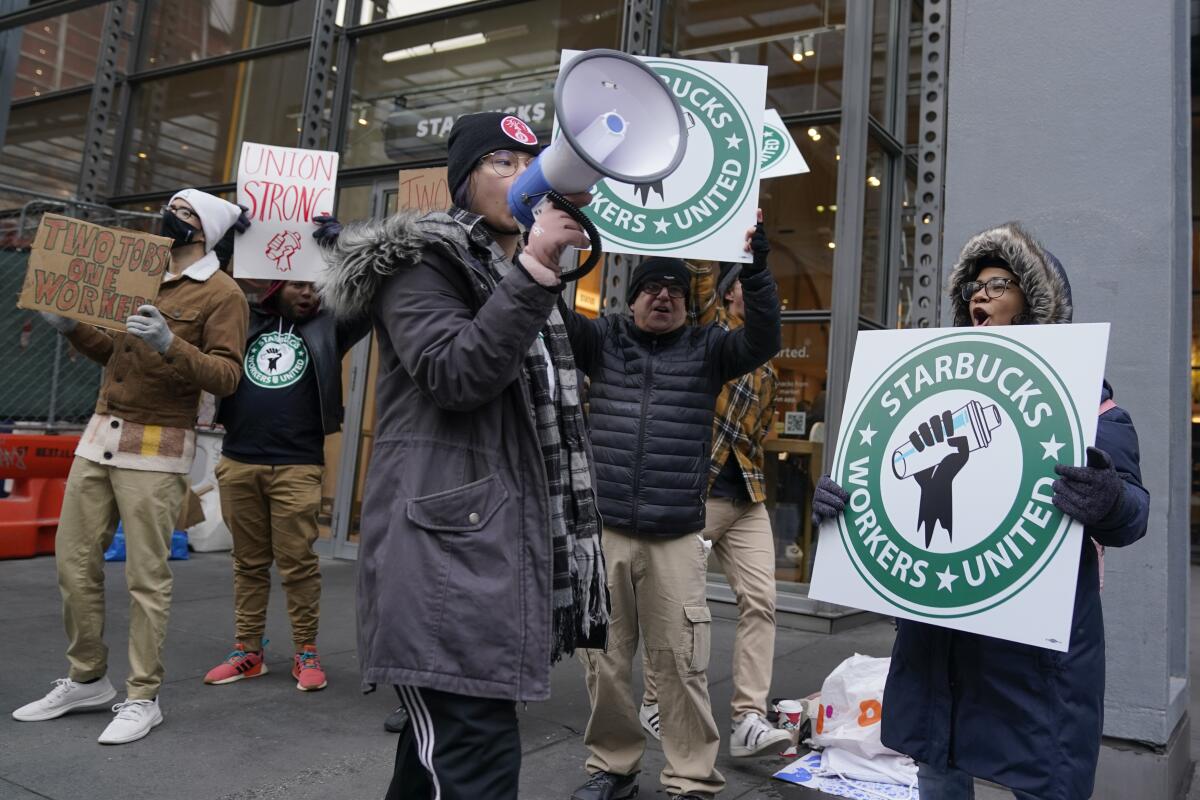 Gente alza carteles frente a un local de Starbucks en Nueva York, jueves 17 de noviembre de 2022. 
