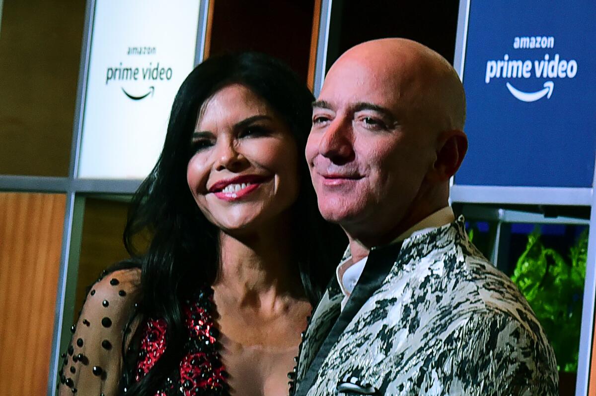 CEO of Amazon Jeff Bezos (R) and his girlfriend Lauren Sanchez (L) pose for pictures as they arrive to attend an event in Mumbai on January 16, 2020.
