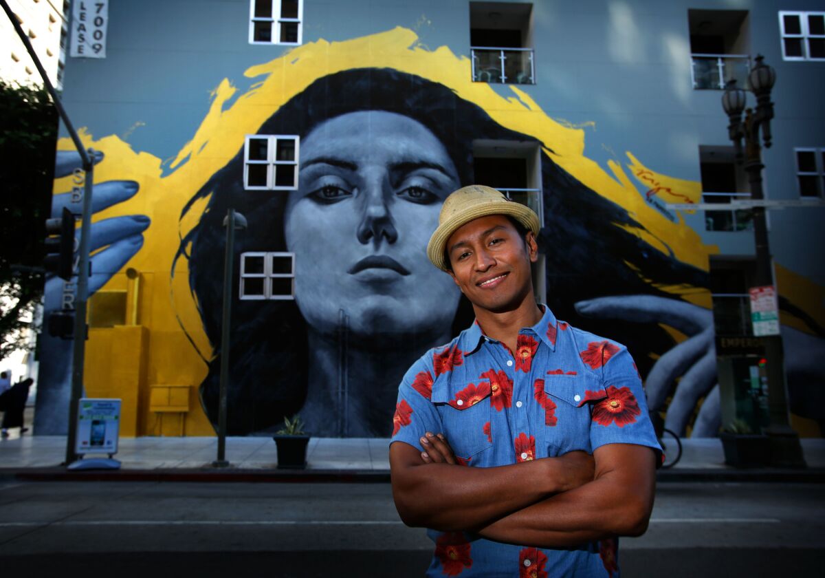 Robert Vargas poses in front of his "Our Lady of DTLA" wall mural at 6th and Spring streets in 2013. (Barbara Davidson / Los Angeles Times)