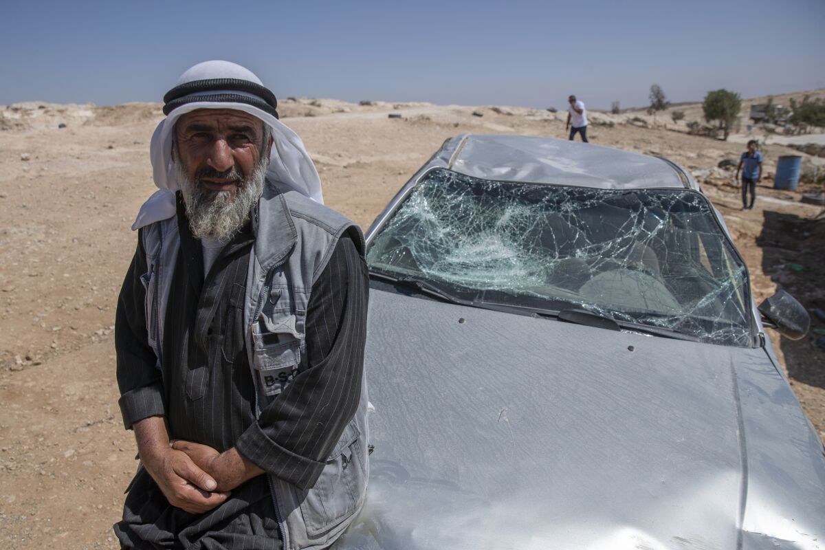A Palestinian man leans on his smashed vehicle following a settlers attack from nearby settlement outposts on his Bedouin community, in the West Bank village of al-Mufagara, near Hebron, Thursday, Sept. 30, 2021. An Israeli settler attack last week damaged much of the village’s fragile infrastructure. (AP Photo/Nasser Nasser)