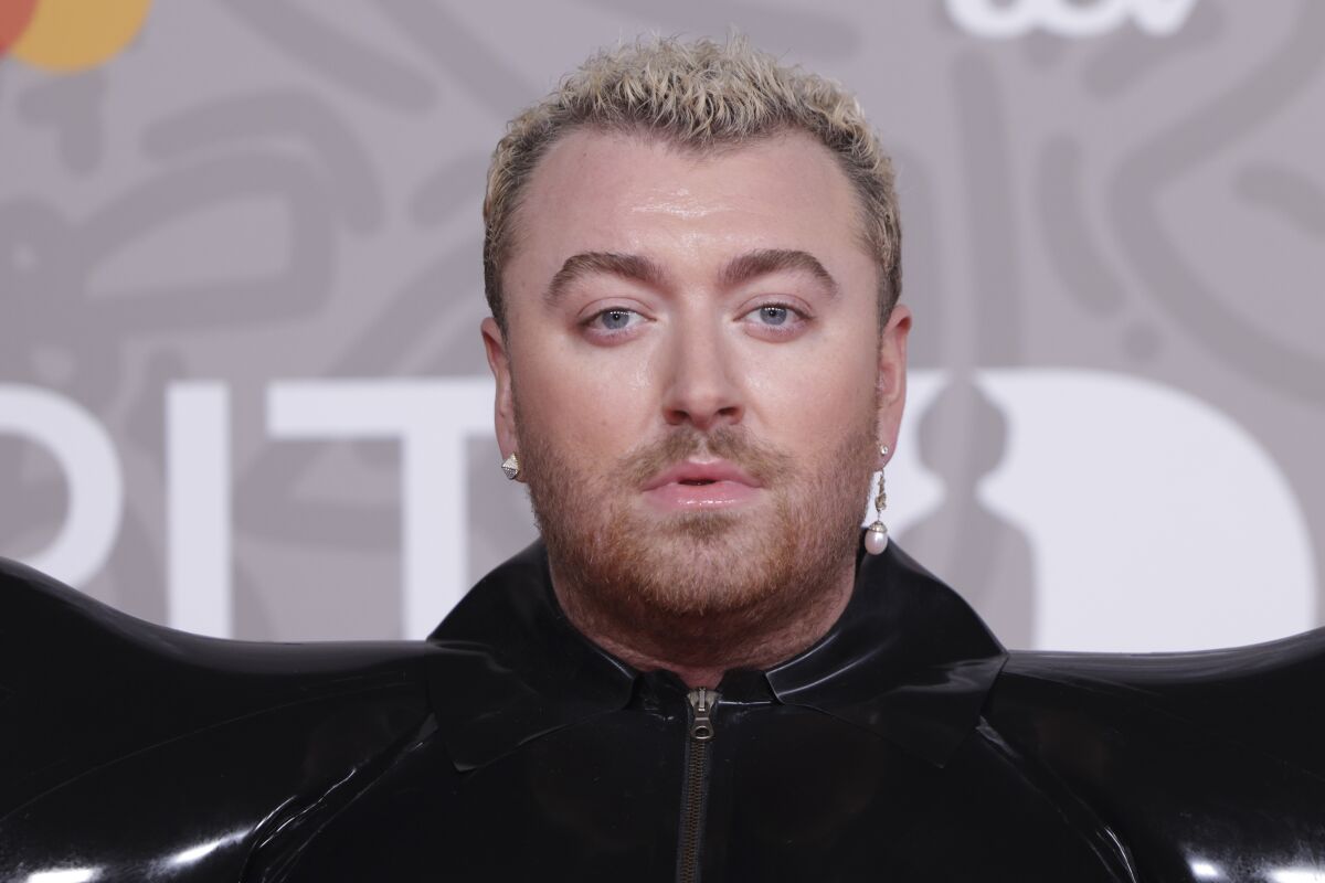 A closeup of Sam Smith with cropped bleached hair, wearing all black