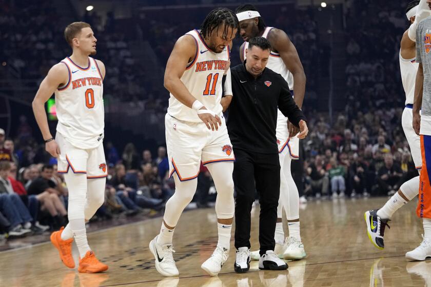 Jalen Brunson (11), de los Knicks de Nueva York, es asistido para abandonar la duela después de sufrir una lesión durante la primera mitad del juego de baloncesto de la NBA en contra de los Cavaliers de Cleveland, el domingo 3 de marzo de 2024, en Cleveland. (AP Foto/Sue Ogrocki)