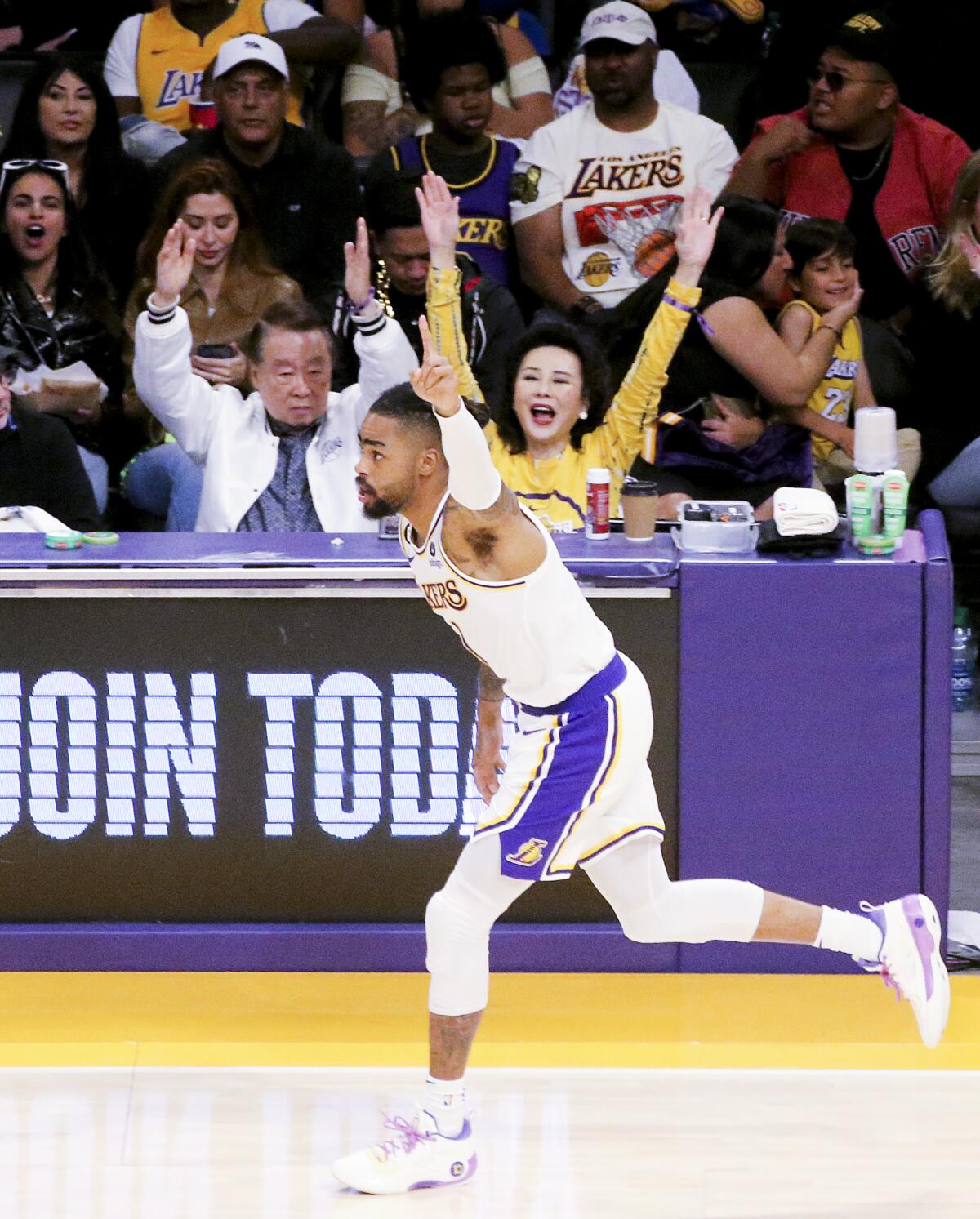 Lakers guard D'Angelo Russell runs up court with his left arm overhead with index finger extended after making a shot.
