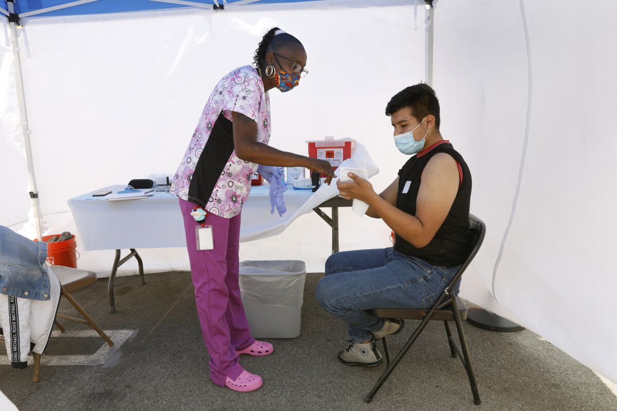 Tanya Mitchell goes over information with Raul Ayala, 18, of East Los Angeles, before giving him a vaccine.