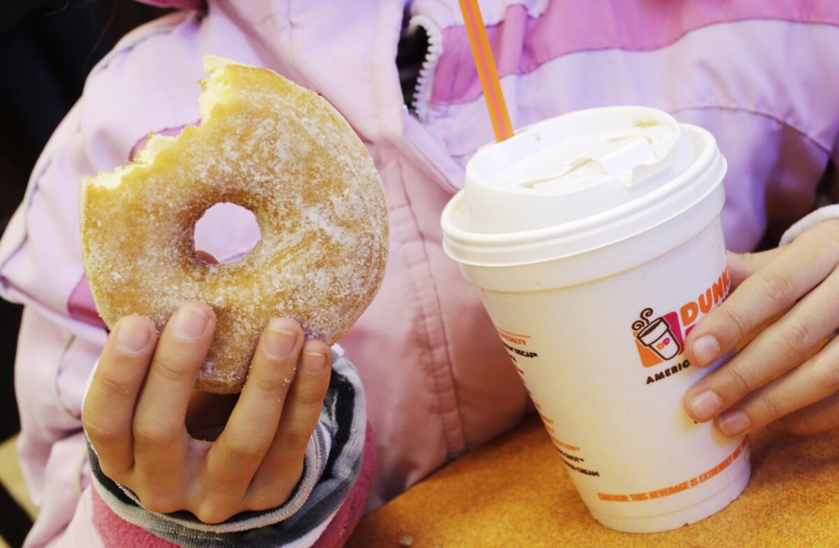 A girl holds a doughnut and a beverage at a Dunkin' Donuts in New York. A Santa Monica location of the doughnut chain is scheduled to open Sept. 2.