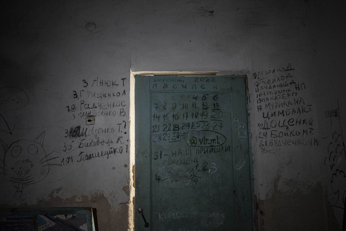 Writing can be seen on a wall and a door in the basement of a school in Yahidne, near Chernihiv, Ukraine, Tuesday, April 12, 2022. Residents say more than 300 people were trapped for weeks by Russian occupiers in the basement of the school in Yahidne. They wrote the names of people who died during the Russian occupation of their village. (AP Photo/Evgeniy Maloletka)