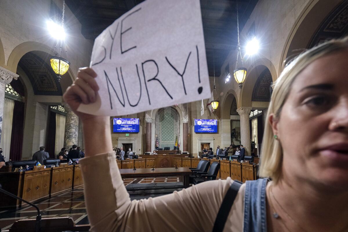 A woman holding a sign protest before the cancellation of the Los Angeles City Council meeting Wednesday, Oct. 12, 2022 in Los Angeles. (AP Photo/Ringo H.W. Chiu)